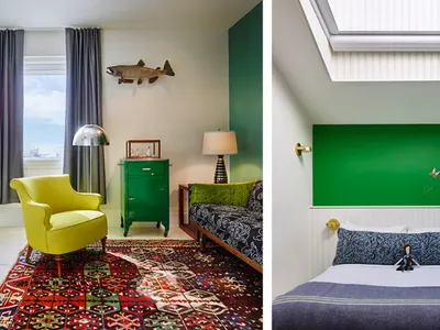 A modern bedroom with a bright yellow armchair, a green dresser, a bed with a green headboard and blue bedding, and a colorfu