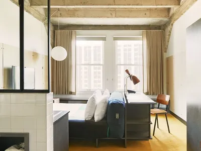 A minimalist bedroom featuring concrete, wood, and fabric materials.