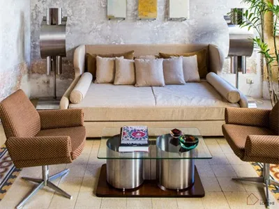 A cozy living room featuring concrete walls, brick pavers, and wooden furniture.