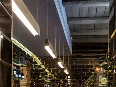 Interior view of a modern industrial restaurant bar with exposed brick walls and a polished concrete counter.