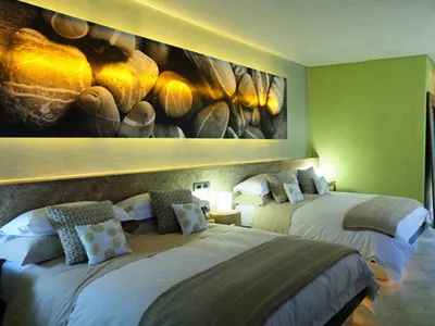 Bedroom with minimalist design featuring concrete furniture and a large wall mural of rocks and light beams.