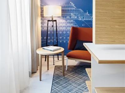 A modern hotel room featuring blue walls, wooden furniture, and a metal lamp.