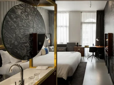 A modern hotel room featuring wood, glass and metal elements.