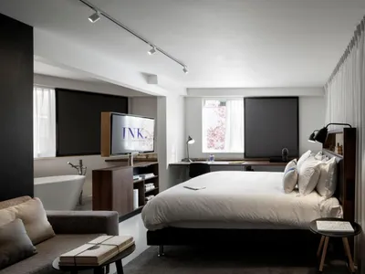 Modern, minimalist bedroom with a large bed, a cozy sofa, and a flat-screen TV.
