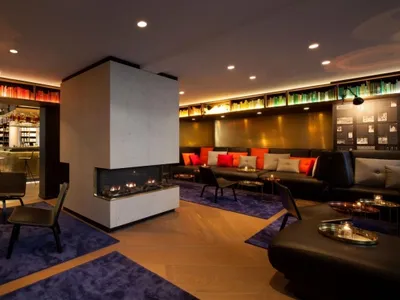 Modern hotel lobby with concrete fireplace, leather seating, and wood accents
