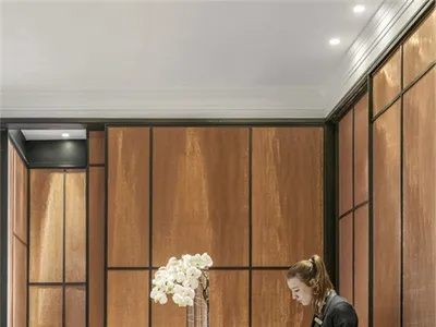 A modern hotel reception area with a wooden desk, glass vase with white flowers, and marble flooring.