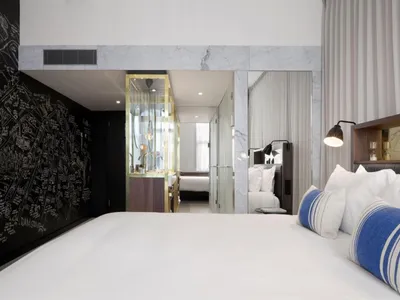 A modern hotel room with white marble accents and a comfortable bed.