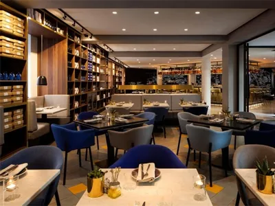 Modern restaurant interior with concrete finish, featuring contemporary furniture and a bar counter.
