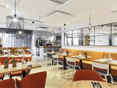 A modern restaurant interior with wood tables, chairs, and flooring.
