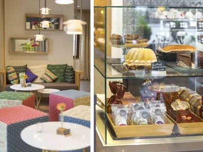 A cozy coffee shop interior with colorful cushions, a glass display case, and various pastries.