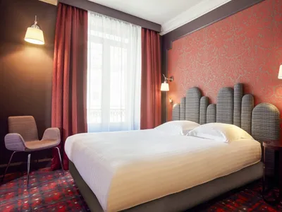 A minimalist bedroom with a white bed, red curtains, and a red patterned wall.