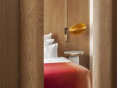 Minimalist bedroom featuring wooden furniture and a red blanket.