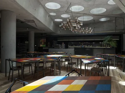 A minimalist restaurant interior featuring concrete walls, wooden floors, and glass elements.