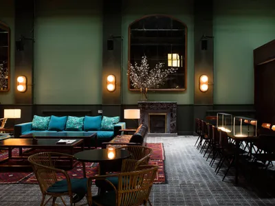 A modern restaurant lounge with marble walls, concrete flooring, and rattan furniture.