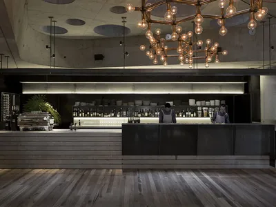 A modern restaurant bar featuring concrete, wood, glass, and metal materials