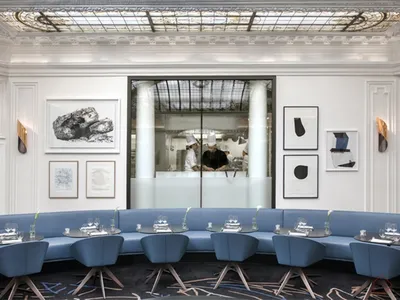 Modern restaurant interior with blue circular seating, white walls, and black-and-white artwork.