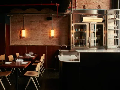 Modern restaurant bar with exposed brick walls, metal accents, and industrial design elements.