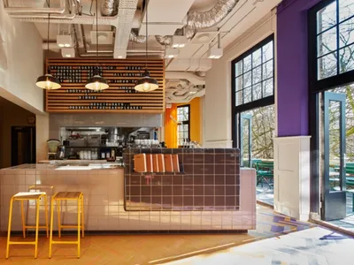 A modern cafe interior with a concrete kitchen bar and tile backsplash.