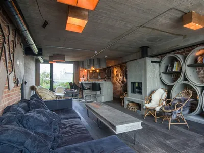 An industrial living room featuring brick walls, concrete flooring, and wooden furniture.