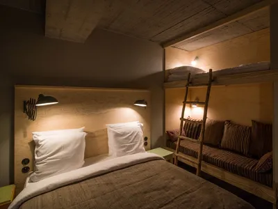 A minimalist bedroom with wooden furniture and a bunk bed with a ladder.