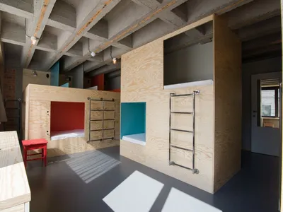 Modern minimalist bedroom with wooden bunk beds and red accents