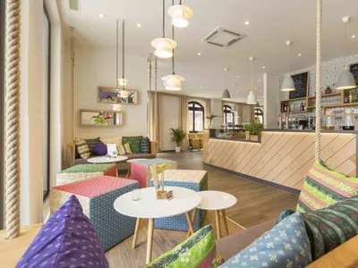 A cozy cafe interior with wooden walls, fabric seating, and metal accents.