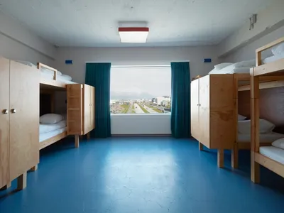 Modern minimalist bedroom featuring wooden bunk beds with view of cityscape through large windows.