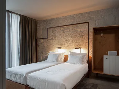 A minimalist bedroom with two twin beds, white sheets, and minimalist design features.