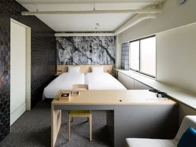 Modern hotel room with a bed, desk, and black hexagonal tile wall