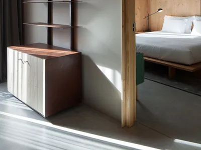 Modern minimalist bedroom featuring a wooden headboard and flooring, with a minimalist design and white bedding.
