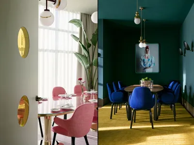 Modern restaurant dining room with round table, blue and pink chairs, round lamps, and yellow rug.