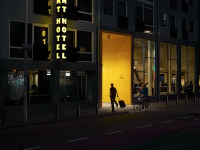 夜間視角的學生旅館入口，入口處有發亮的招牌與黃色燈光照明。