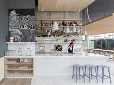Modern restaurant bar interior with marble countertops, concrete walls, and hanging pendant lights