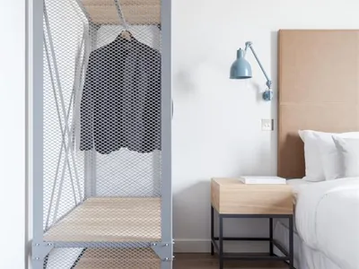 Industrial-style bedroom with floating wooden shelves, modern bed, and minimalist decor.