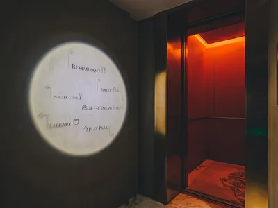 Hotel elevator entry with metal doors and illuminated signage.