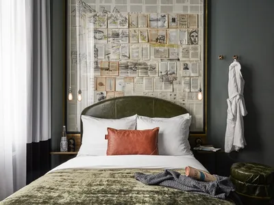 A well-designed modern bedroom featuring a concrete floor, a bed with a leather headboard, and a fabric bedspread.