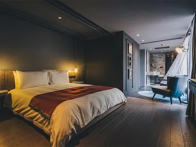 Modern bedroom with concrete accent wall, wooden flooring, and minimalistic decor.