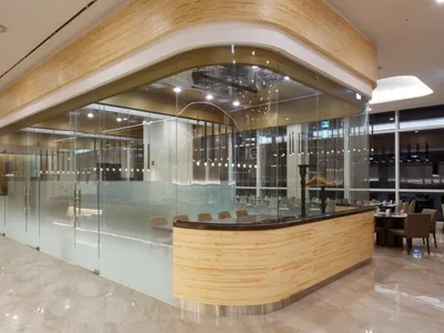 A modern restaurant with glass walls, marble flooring, and wooden accents.
