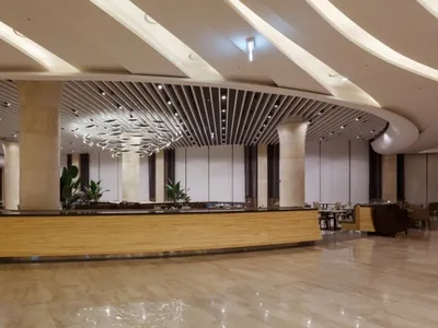 Modern hotel reception with marble circular ceiling panel and wooden counter.