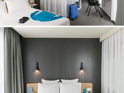 Modern minimalist hotel bedroom suite with textured dark grey walls, white bedding, and a sink with a towel rack.