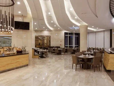 Modern restaurant interior with marble flooring, seating arrangements, and tables.