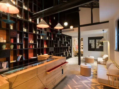 A modern hotel reception area featuring timber, concrete, and ceramic materials.