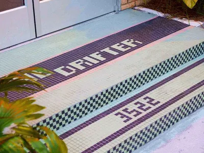 A detailed view of a hotel entrance with a geometric tile design in shades of blue, green, and black.