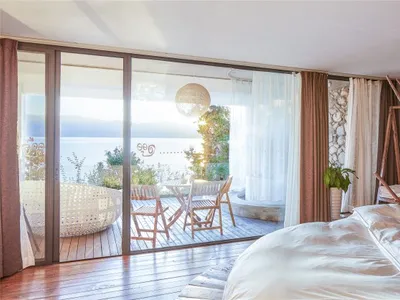 White minimalist bedroom featuring wood flooring, stone wall, and canvas lighting fixture.