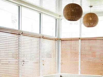 Modern restaurant interior with wooden tables, fabric seating, and glass pendant lights.