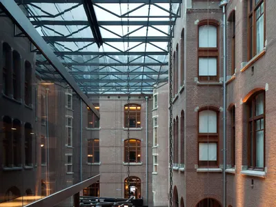 Indoor hotel lobby featuring exposed brick walls, glass walls, and modern furniture.