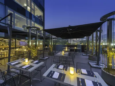 戶外用餐區配有金屬家具、玻璃欄杆與混凝土地板，餐桌已擺設餐具與罐子