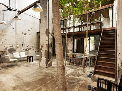 An industrial-minimalist living room with concrete walls, wooden furniture, and steel accents.