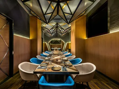 Long dining table with blue and white cushioned chairs in a modern industrial restaurant setting