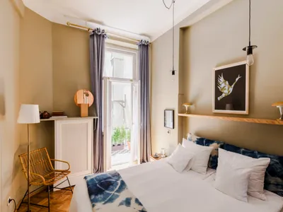 A minimalist bedroom with blue walls, swan artwork, and alternating hanging light bulbs.